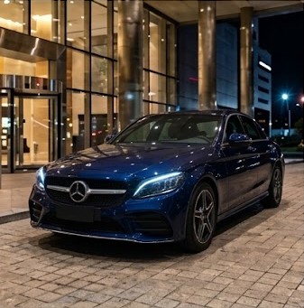 Sedán Mercedes-Benz azul frente a la entrada de un hotel de noche